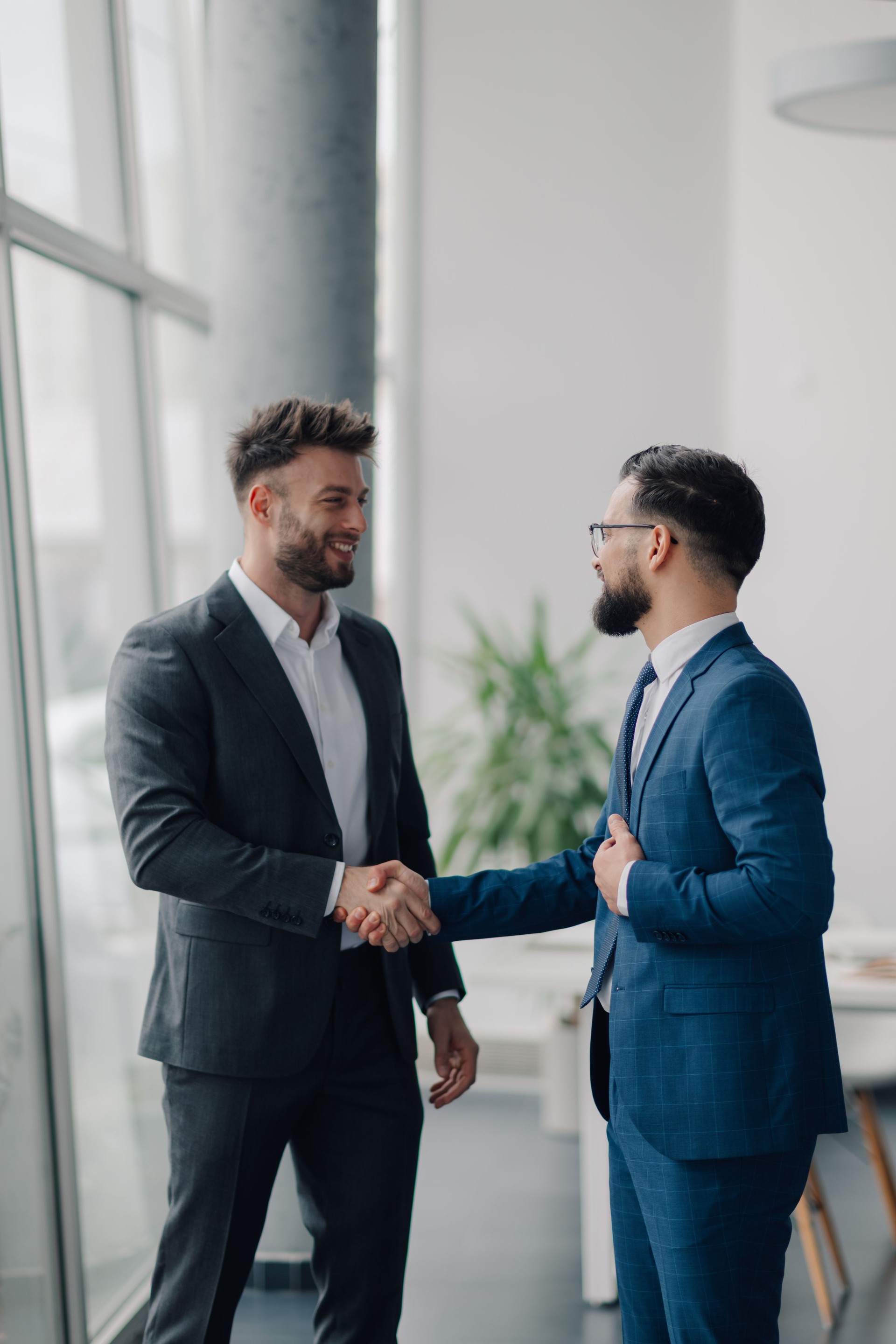 Two smiling businessmen shaking hands in modern office